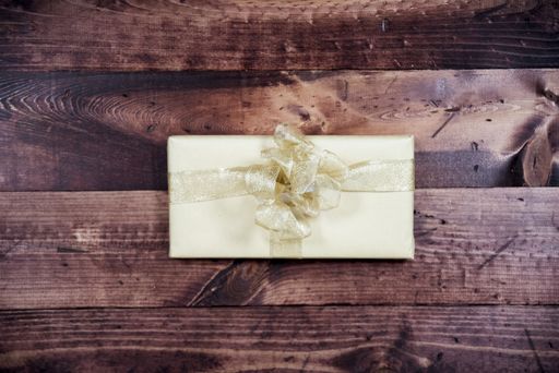 An overhead shot of a present with golden ribbon on a wooden surface