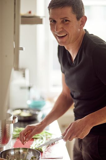 A vertical shot of a white German man cooking