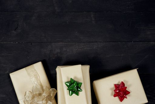 An overhead shot of present with different color bows on a black wooden surface