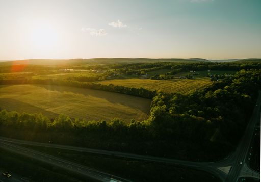The beautiful drone landscape over lush farm fields and highways under sunset sky in Pennsylvania