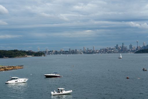 An aerial view of yachts moored in the bay with the Sydney skyline in the background