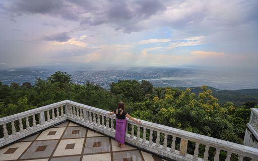 A woman stands on the balcony at Wat Phra That Doi Suthep Buddhist Temple overlooking the Chiang Mai area.