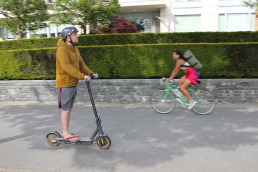 A Young man riding electric scooter in downtown Vancouver, British Columbia, Canada