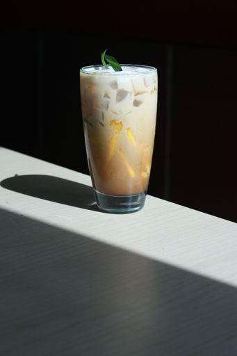 A vertical shot of a glass of iced drink on a dark surface under the light