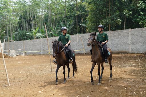 Two boys practice riding on a horse
