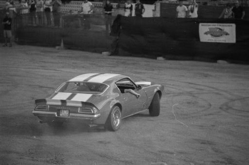 A grayscale shot of Pontiac Firebird Trans AM car driven on a dirt raod