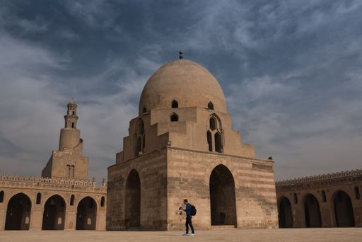 A man standing in front of the ancient Ibn Tulun Mosque in Cairo, Egypt