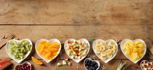 Heart-shaped fruit plates on rustic wooden background with space for thext