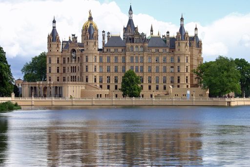 A scenic view of Schwerin Castle in Schwerin, Germany with a lake in the foreground