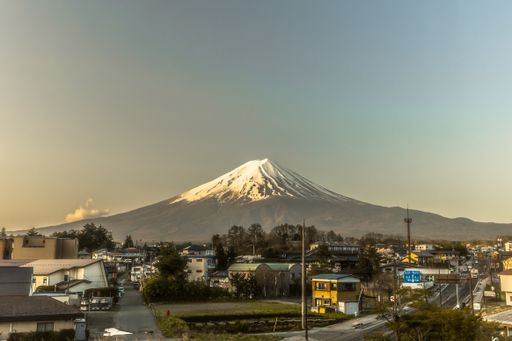 A beautiful shot of buildings and a mountain with a snowy top in the distance under a blue sky