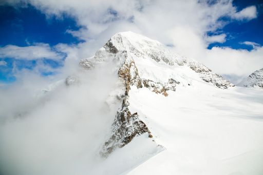 A beautiful shot of snowy mountains with a blue cloudy sky in the background