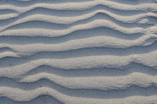 A closeup shot of beach sand with deep wavy line patterns
