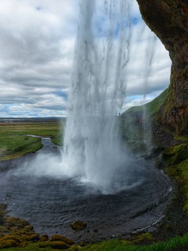 Seljalandsfoss is one of most beautiful and famous waterfalls on Iceland.Beautiful view of waterfall and rocks covered with moss under blue cloudy sky