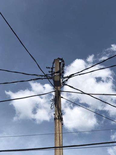 An electric post with wire on a cloudy sky background
