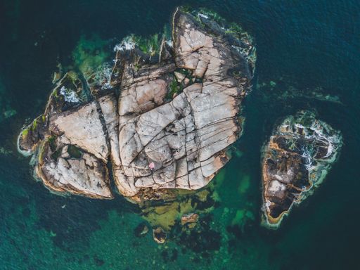 Aerial shot of a rocky island in an ocean shot with a drone