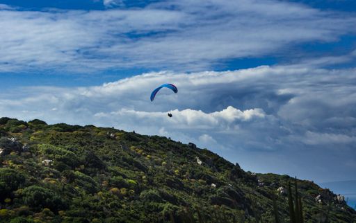 A beautiful shot of a man paragliding over a mountainous landscape
