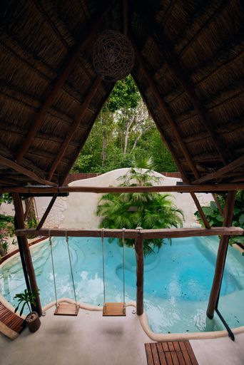 A vertical shot of a cozy hut with swings and a pool under its wooden roof in Tulum, Mexico