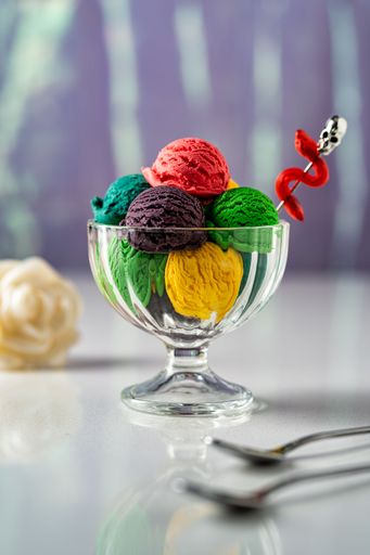 A vertical shot of a glass cup full of colorful ice cream scoops - concept of restaurant