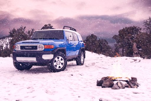 A scenic shot of a 2007 Toyota FJ Cruiser in blue on a mountain during a snow storm