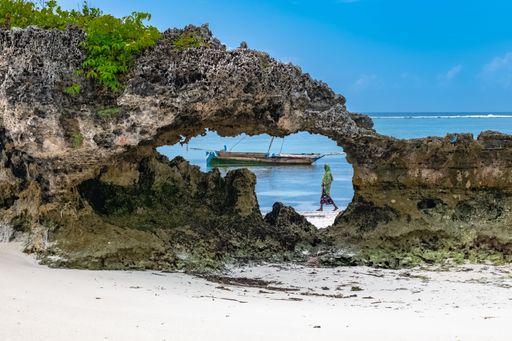Beautiful cliff on the beach over a background of a boat sailing in the ocean, Zanzibar, Africa