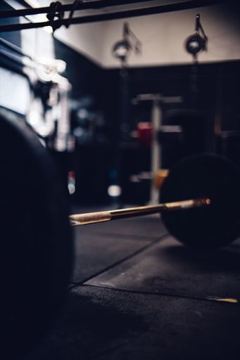 A vertical closeup shot of a barbell on the floor of a gym