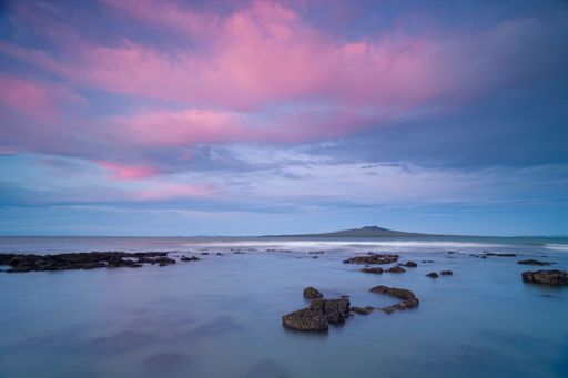 Setting sun highlights clouds with a pink hue, Rangitoto extinct Volcano in background