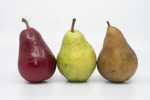 A closeup shot of different color pears on a white surface