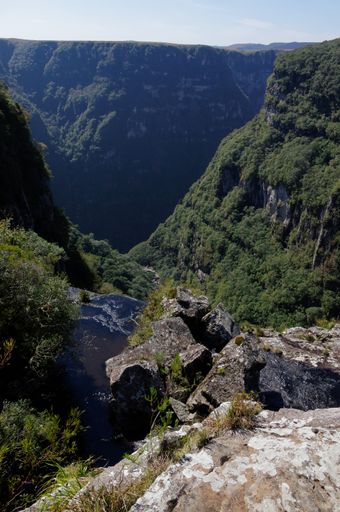 A vertical shot of green mountainous scenery with a small lake under the clear sky