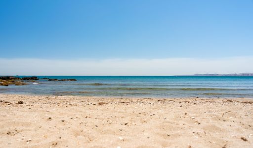The view of the sand before the sea under the blue sky on a sunny day