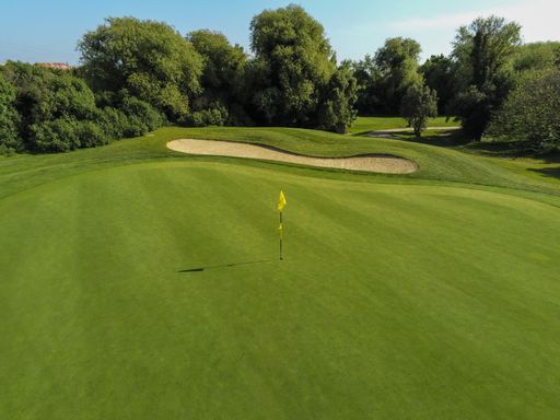 Aerial view from a golf course where we can see a flag signaling the hole