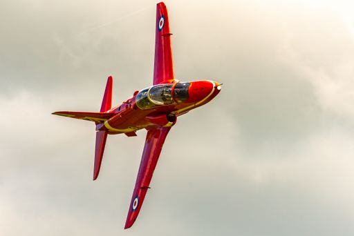 A closeup shot of a red plane flying in the air on a sunny day