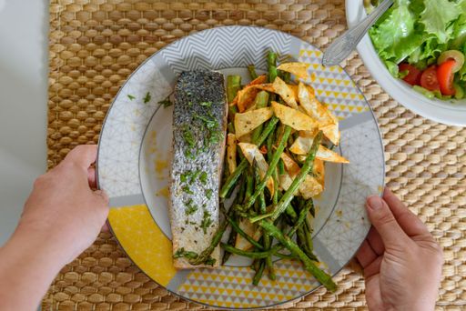 A top view of person holding plate with grilled salmon and asparagus