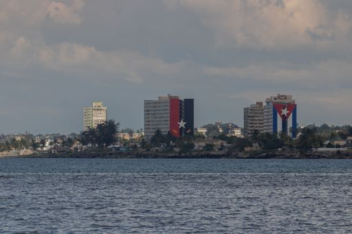 A scenery of 13-story buildings with the Cuban flag behind the sea, Matanzas, Cuba