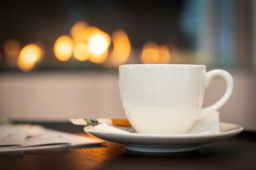 A shallow focus shot of a white coffee cup with a blurry background of bokeh effects
