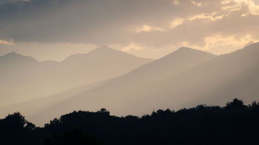 A silhouette of mountains in sunset light with some misty fog