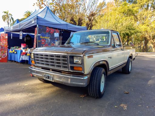 Quilmes, Argentina - May 29, 2022: Old beige and white utility Ford Ranger F 100 pickup truck 1980 - 1981 in a park. Nature, trees. Classic car show.