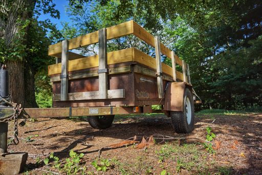 An old and rusty farm wagon among the greenery at daytime