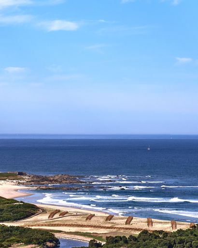 A vertical shot of the coastline of a resort area with sandy beaches and nearby town, Portugal