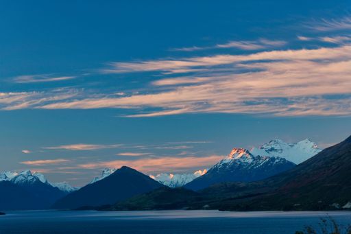 late afternoon sun illuminates the rugged, snowcapped 2,819m peak with head of Lake Wakatipu, Mount Aspiring National Park, New Zealand