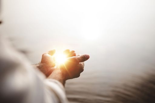 A beautiful shot of Jesus Christ holding hope and light in his palms with a blurred background