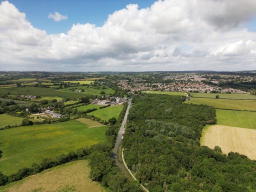 An aerial view of a canal in a green field against a town on a sunny day
