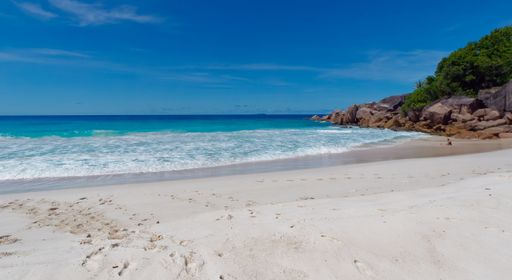 A beautiful shot of sandy Petite Anse beach in Seychelles with foamy waves on a sunny day