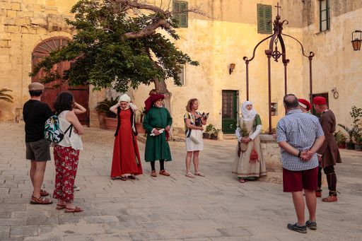 A lady dressed in a period costume as a herbalist explains to an audience herbs and their uses in a reenactment of 15th century life at Mdina, Malta,