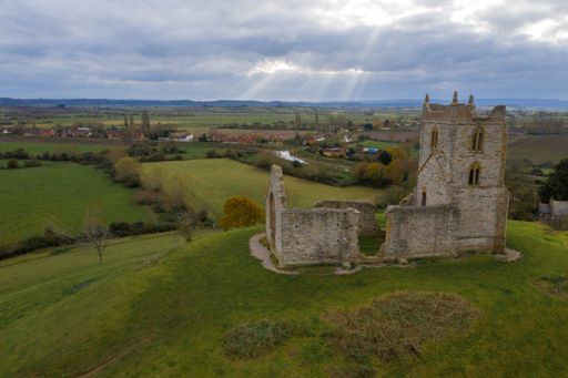 An aerial shot of Burrow Mump a hill and historic site overlooking Southlake Moor in Burrowbridge village within the English county of Somerset
