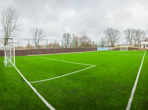 A closeup of green soccer field with gate under cloudy sky