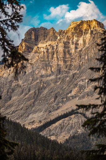 A Beautiful rocky mountain with sunlight and cloudy blue sky at Banff National Park in Alberta, Canada
