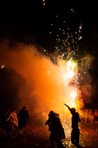 A vertical shot of people dancing around fireworks during the Corpus Christi patronal festival