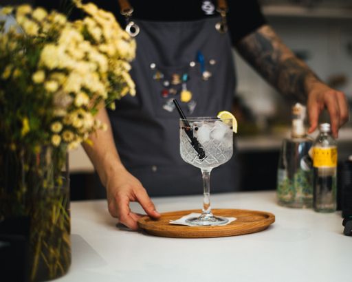 A tasty cocktail with ice and straw in a bar with a bartender
