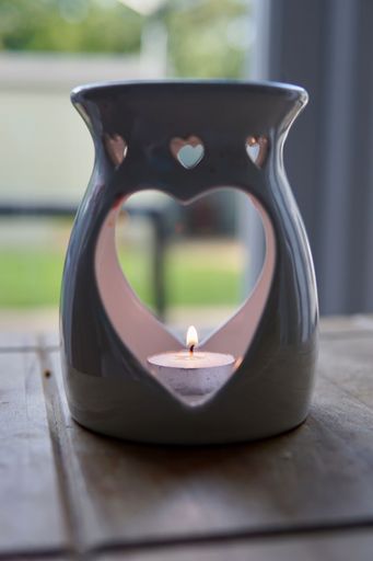 A ceramic, a heart-shaped candlestick with a burning candle, vertical