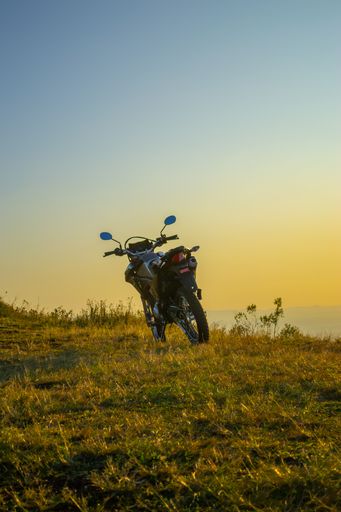 A vertical shot of a motorcycle in the grass during sunset